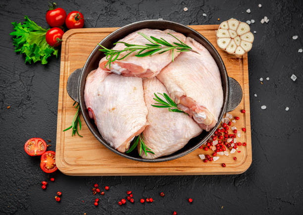 Raw bone-in chicken thighs in bowl with rosemary garnish