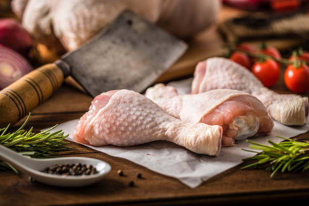 Chicken drumsticks on parchment with herbs and seasoning, raw 4-pack bundle