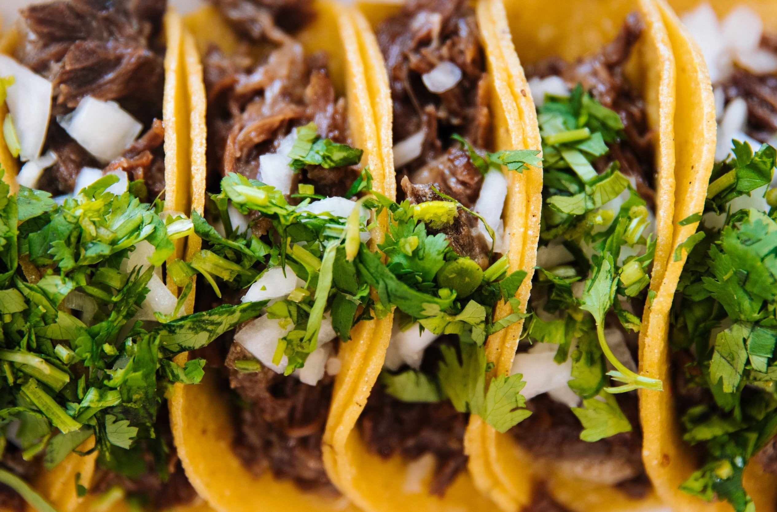 Skirt steak tacos with chopped cilantro and onions on yellow corn tortillas