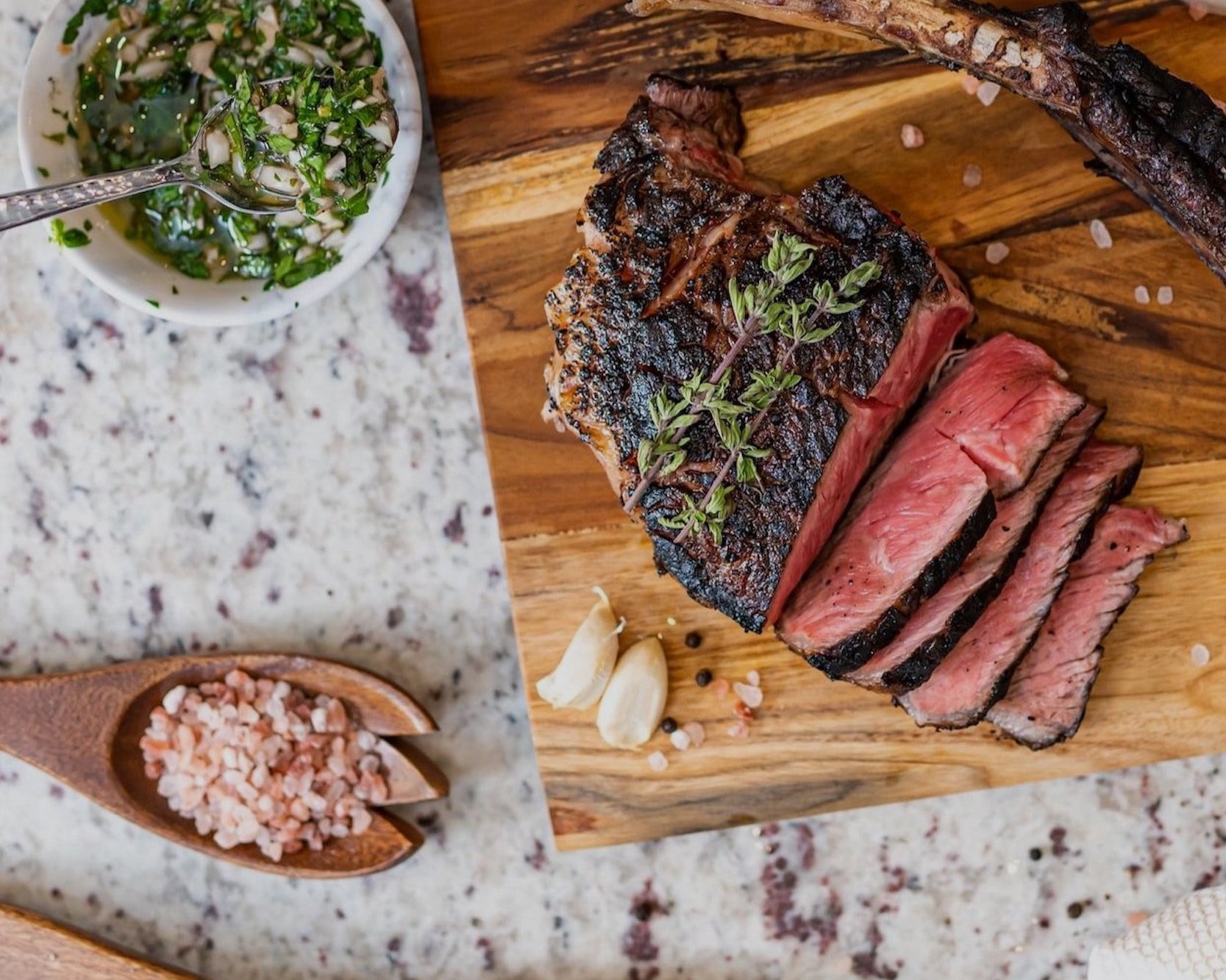 Grilled flank steak slices on wooden board with fresh herbs