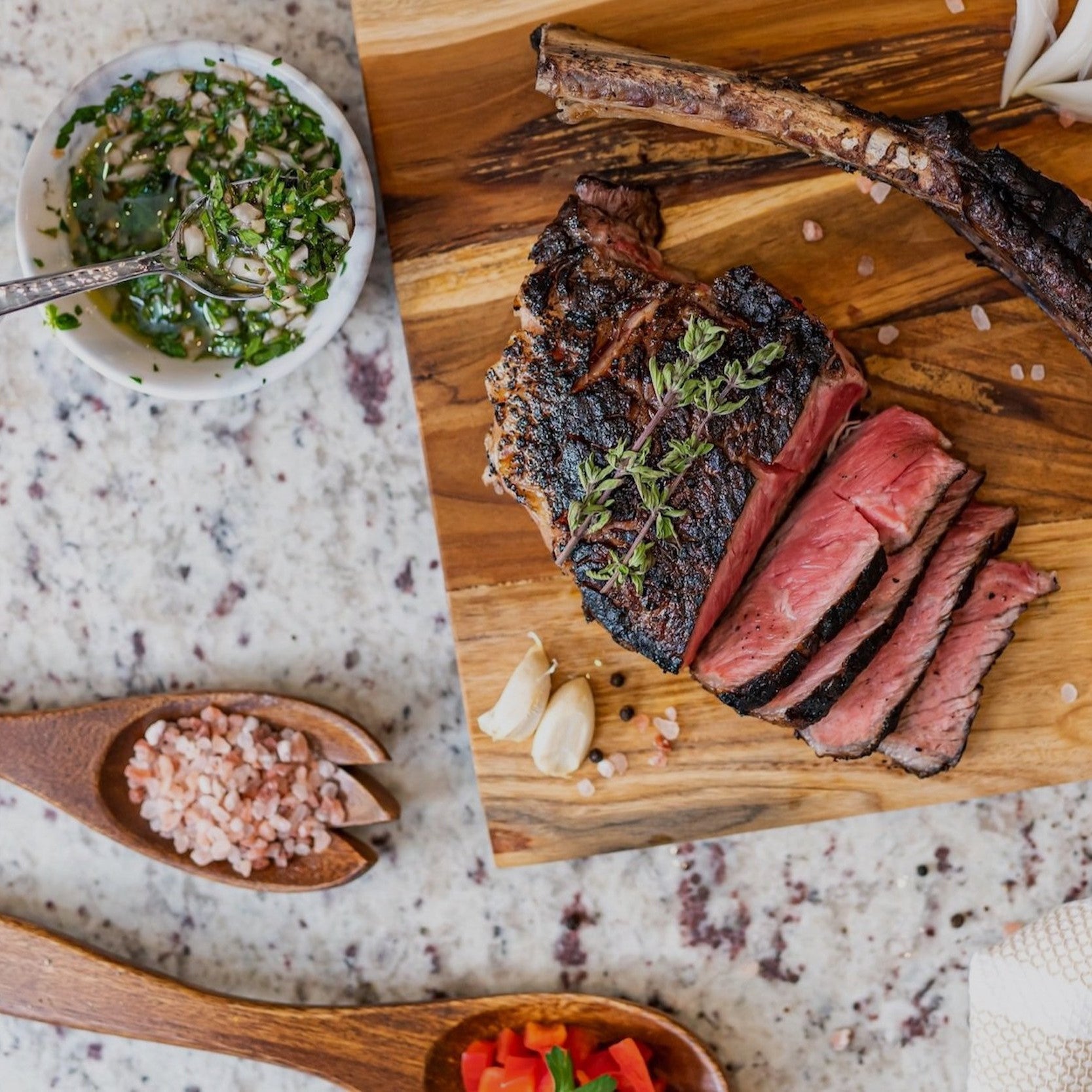 Grilled flank steak slices on wooden board with fresh herbs