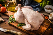 Two whole raw chickens on a wooden cutting board, ready for roasting