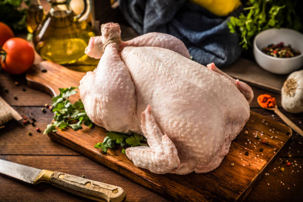 Two whole raw chickens on a wooden cutting board, ready for roasting