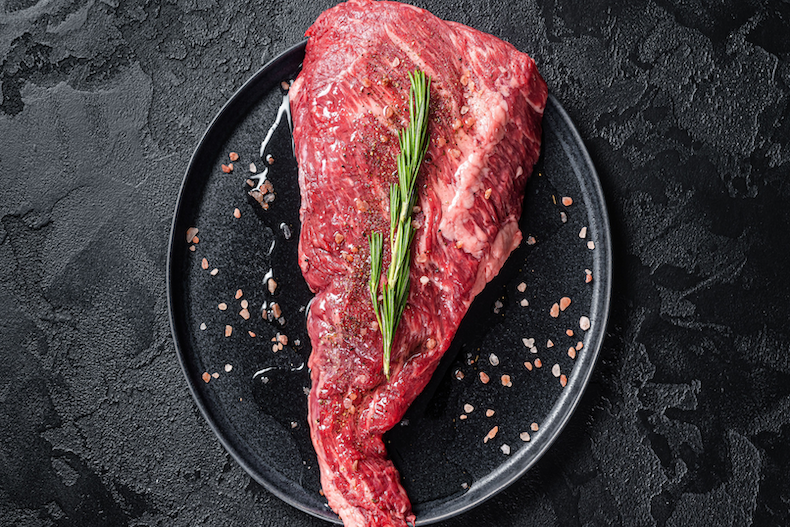 Raw tri-tip steak with visible marbling and fat cap, ready for roasting or grilling