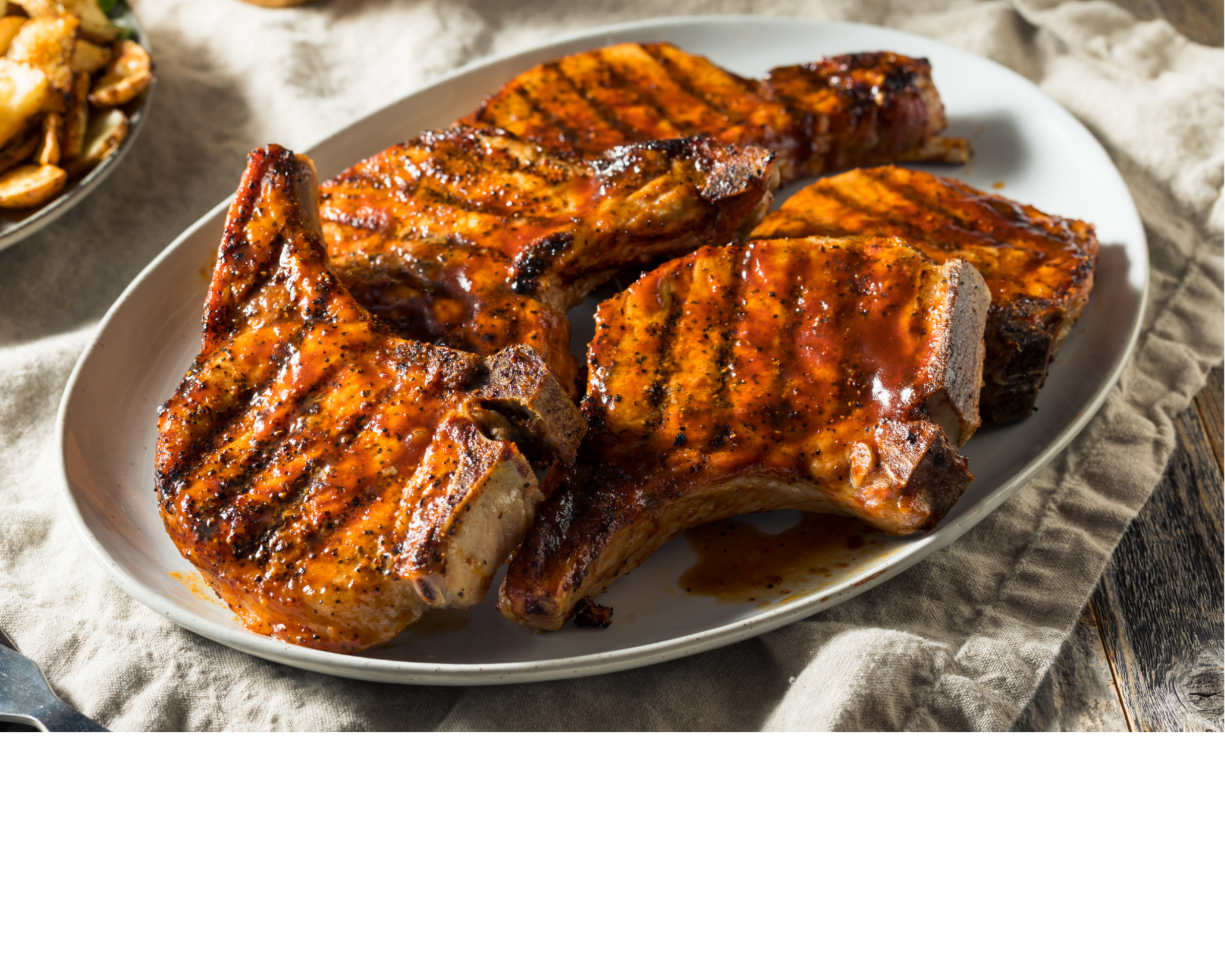 Grilled bone-in pork chops on a plate, charred surface and seasoning
