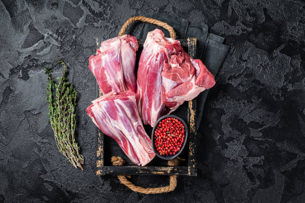 Raw lamb shanks on wooden rack, with visible bone and cut meat