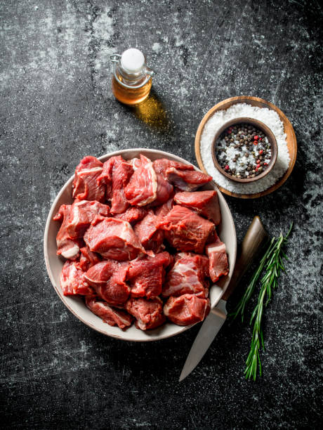 Bowl of raw lamb stew meat, red chunks with visible marbling and bone pieces