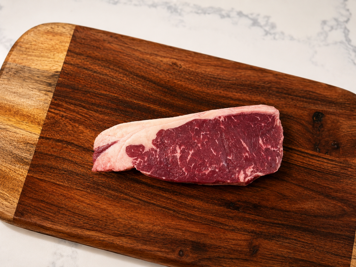 KC strip steak on wooden cutting board, raw marbled beef