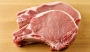 Raw bone-in pork chops, pink-red meat with marbling