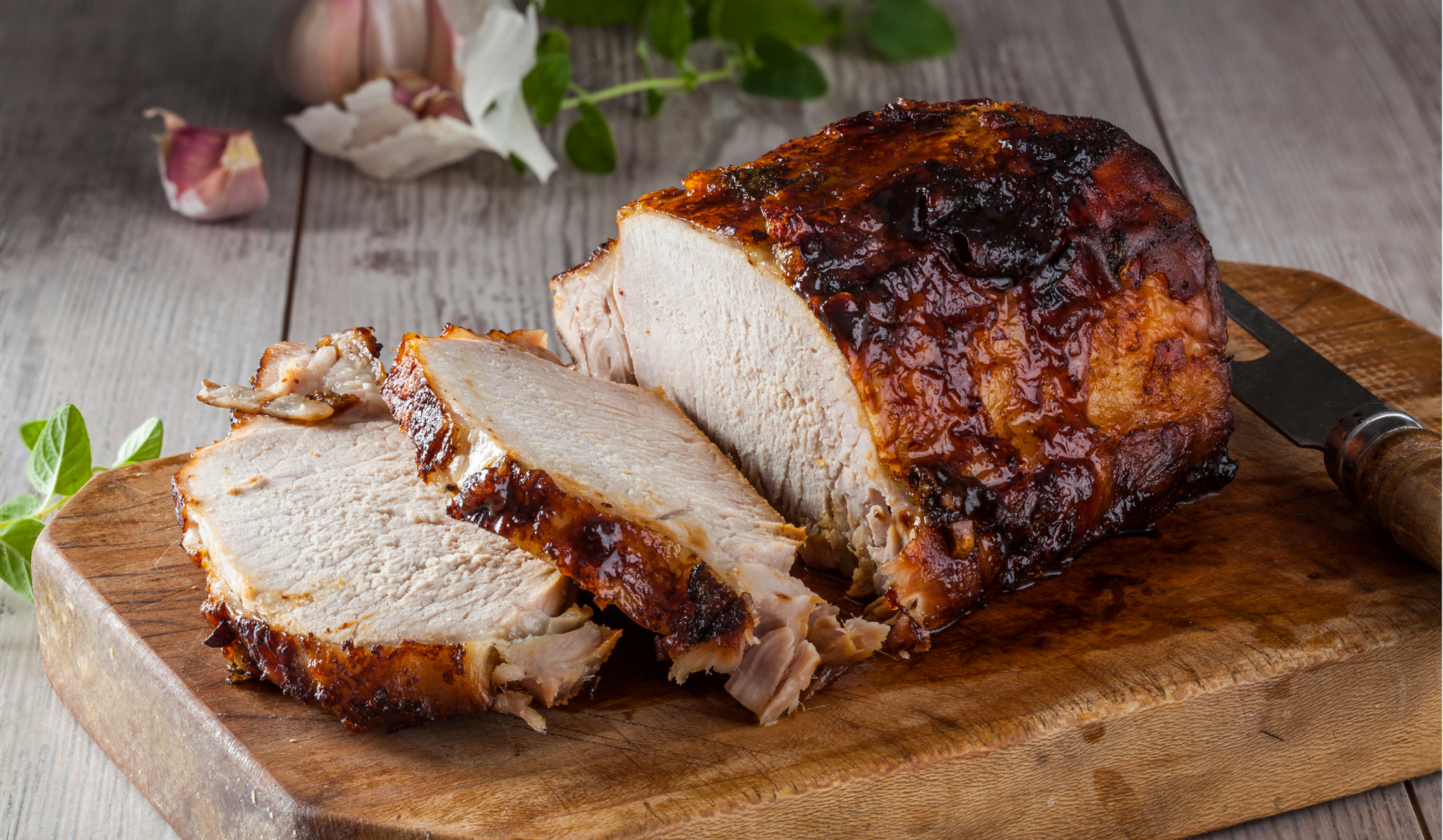 Roasted pork roast with sliced center on wooden board, browned exterior