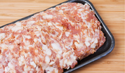 Raw pork sausage on black tray, sliced pieces with visible white fat