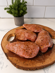 Seasoned boneless skinless chicken breast fillets on wooden cutting board